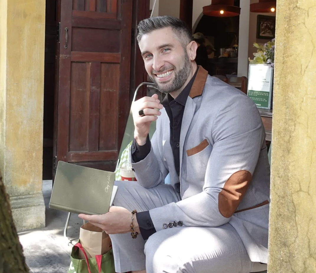 Michael Ostrow smiling while seated with a notebook in Hoi An, Vietnam